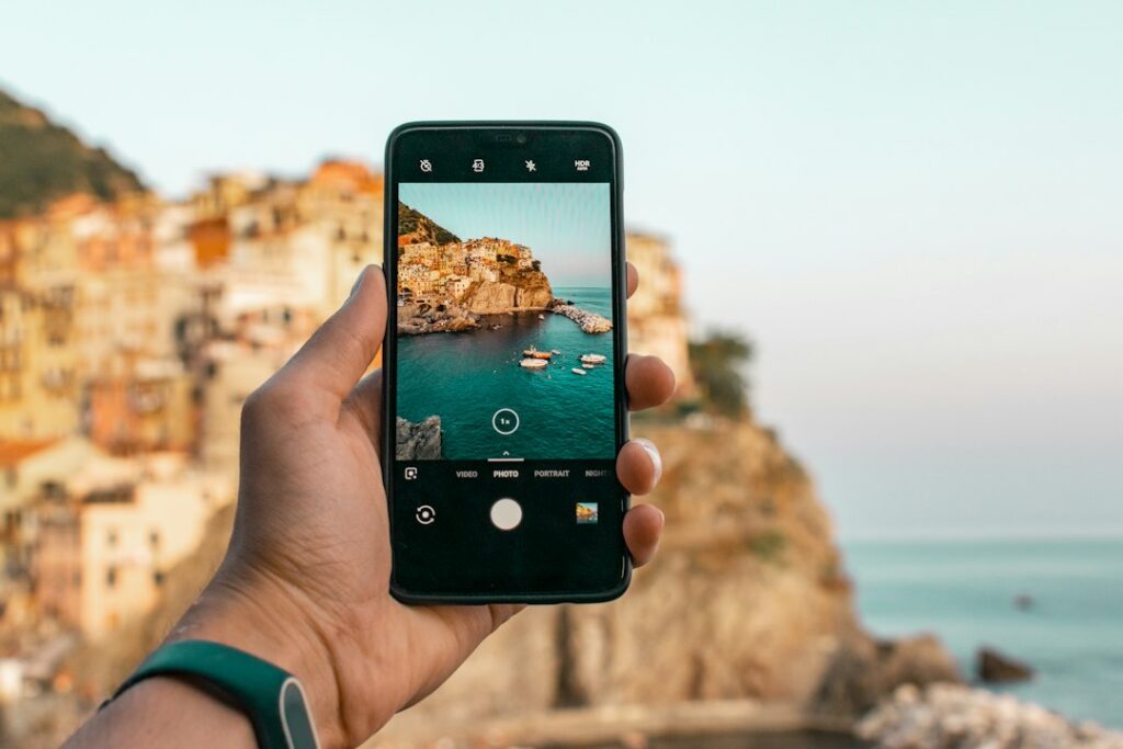 A person using a smartphone camera to photograph a coastal scene