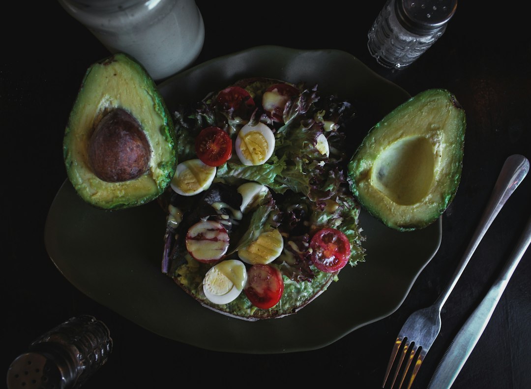 Avocado halves and a vegetable salad on a dark plate