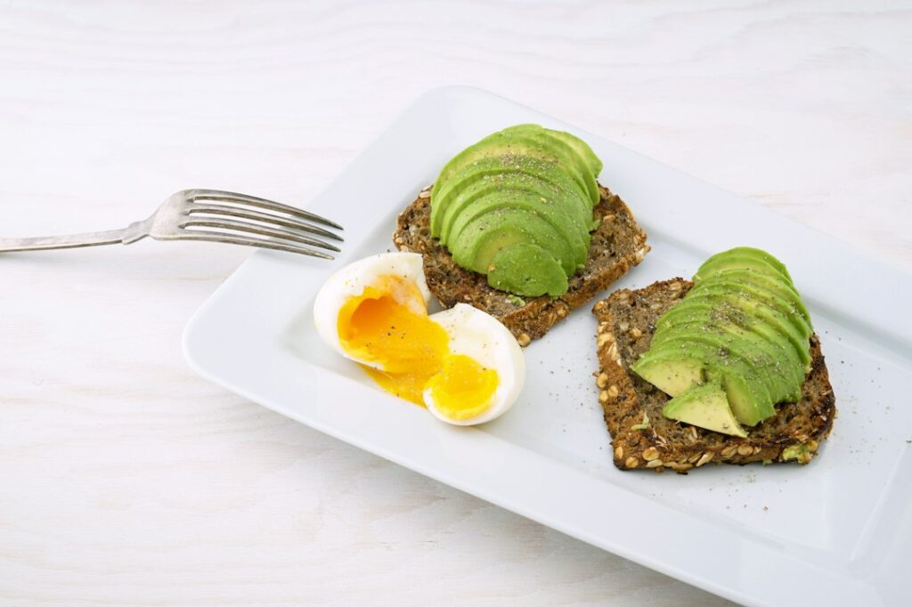 Avocado toast with egg on a white plate
