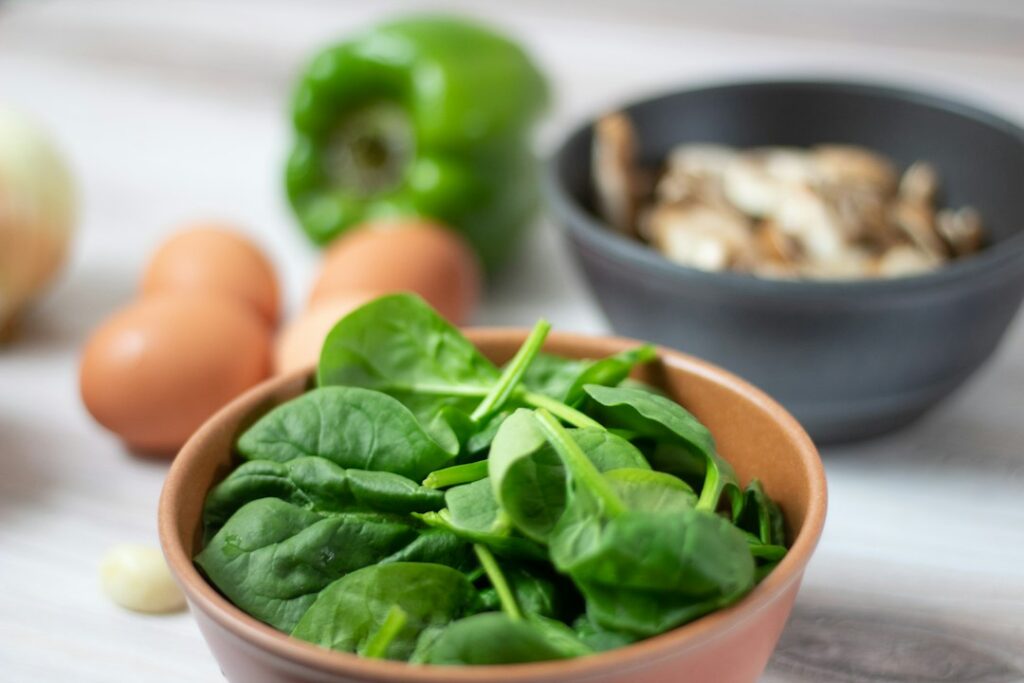 Fresh spinach, eggs and vegetables prepared for an omelet