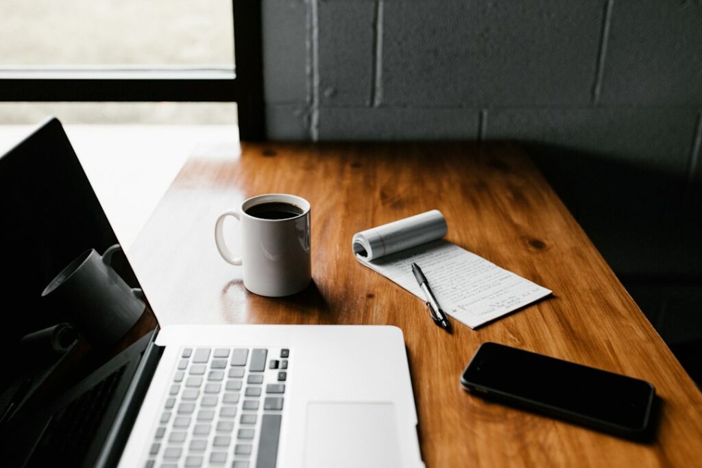 Laptop, phone and notebook on a wooden desk