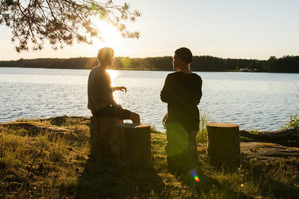 Two people talking beside a lake at sunset